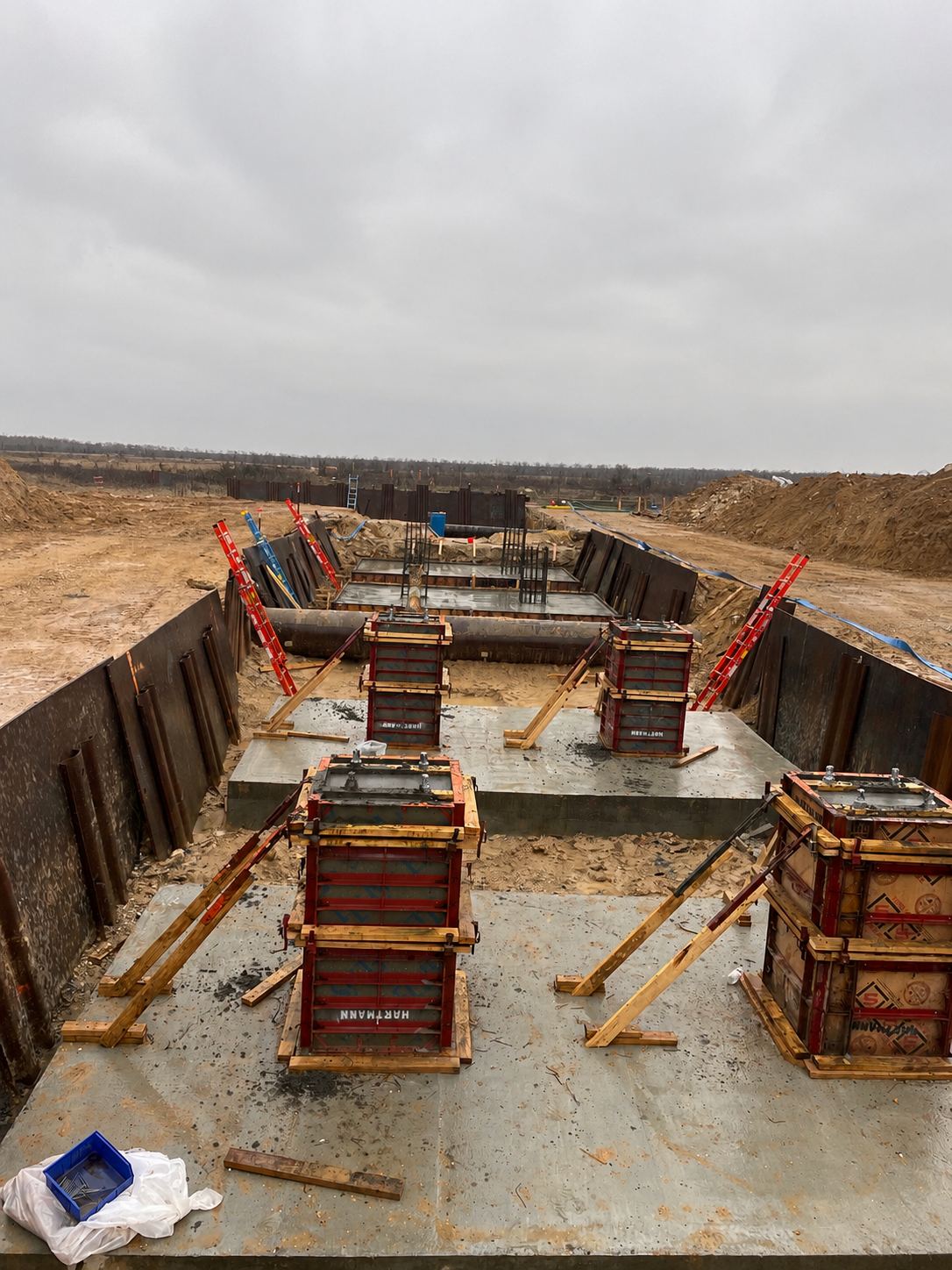Concrete pier forms set on completed foundation slabs in a shored excavation